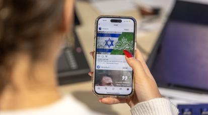 Eine Frau scrollt durch Instagram und betrachtet einen Beitrag über den Nahostkonflikt.