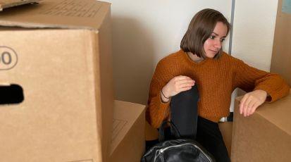 Eine junge Frau sitzt in ihrer Wohnung zwischen Umzugskartons. (Symbolbild) | Bild: Tabea Blume und Alice Kärcher                   