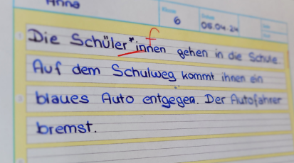 Diktatheft, in welches mehrere Sätze geschrieben sind. Das Wort Schüler*innen ist als Fehler angestrichen. 