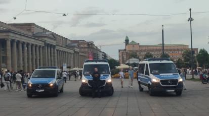 Ein Polizist steht mittig vor drei Polizeiwägen