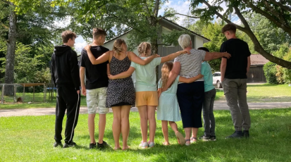 Die Bewohner aus Haus acht stehen im Garten Arm in Arm