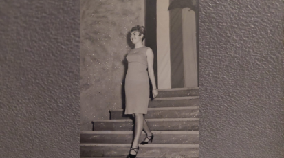 Meine Oma trägt ein Kleid und hohe Schuhe. Sie läuft eine Treppe hinunter und lacht dabei.