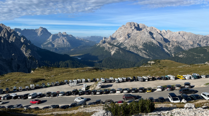 Voller Parkplatz im Hintergrund Berge.