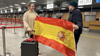 Mit Koffer, Sparschwein und Spanienflagge am Flughafen