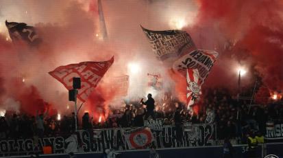 Roter Rauch über der Fankurve. Ultras zünden Pyrotechnik.