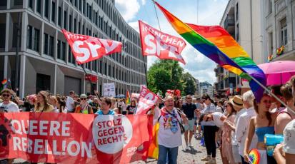 Eine Gruppe Menschen hält ein SPD-Banner und SPD-Fahnen auf dem CSD.