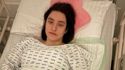 Eine junge Frau liegt in einem Krankenhausbett.
