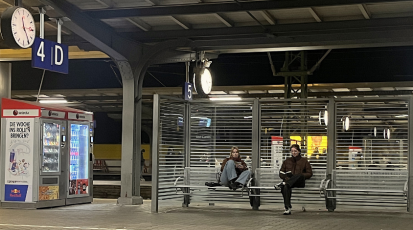 Zwei Leute warten am Bahnhof.