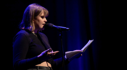 Auf der Bühne, mit dem Mikro vor sich und ihrem eigenen Text in der Hand, steht Evelyn beim Poetry Slam
