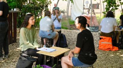 At an outdoor-event, people sit together in pairs of two and have conversations.
