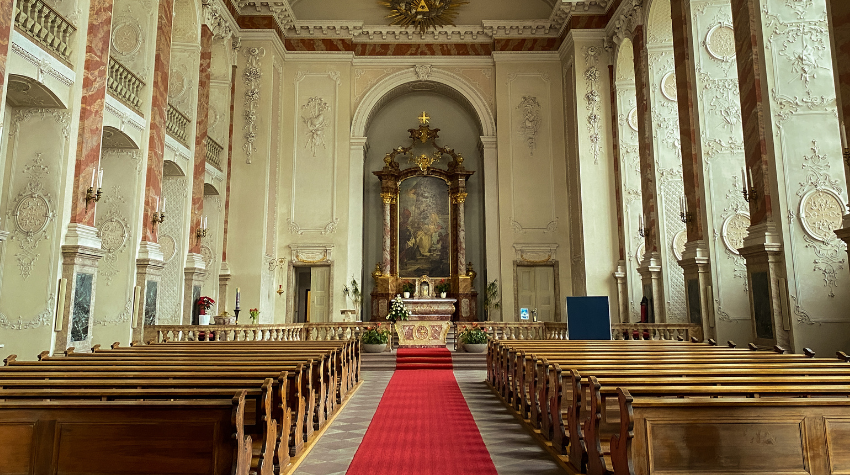 Das Bild zeigt die Schlosskirche in Mannheim. In der Mitte der Altar. Die Bänke rechts und links sind noch leer.