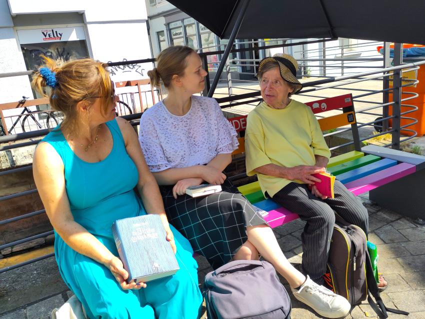 People talking to each other on a colorful bench.