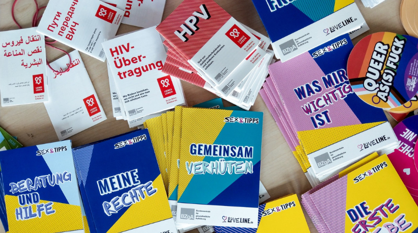Auf einem Tisch liegen viele Infomaterialen der AIDS-Hilfe und der BZgA.