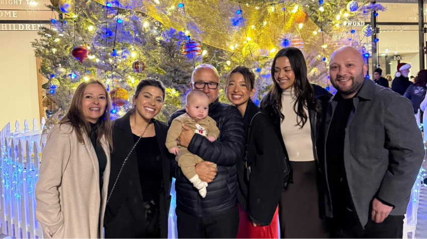 Stephanie und ihre Familie posieren lächelnd vor dem Weihnachtsbaum