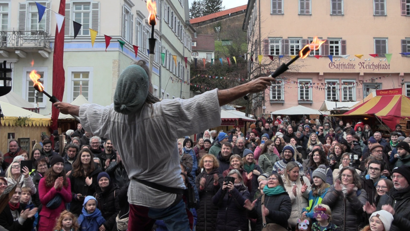 Jongleur "Master Fleapit" jongliert mit Feuer, die Zuschauer sind begeistert.