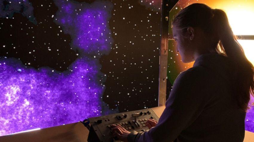 Bildschirm mit Galaxie (links) und Frau (rechts), die auf Galaxie schaut