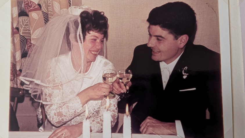 Oma und Opa stoßen an ihrer Hochzeit mit einem Glas Wein an.