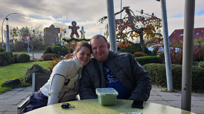 Tatjana und ihr Freund Manuel sitzen auf der Terrasse und lächeln in die Kamera