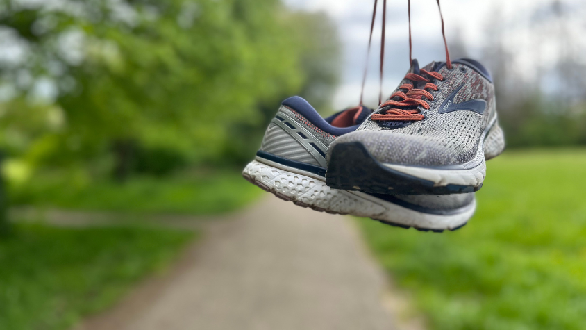 Baumelnde Sportschuhe vor einer grünen Kulisse