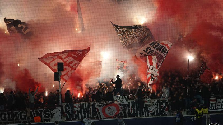 Roter Rauch über der Fankurve. Ultras zünden Pyrotechnik.