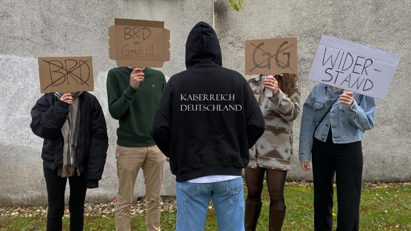 Symboldbild einer Reichsbürger-Demo mit Schildern.