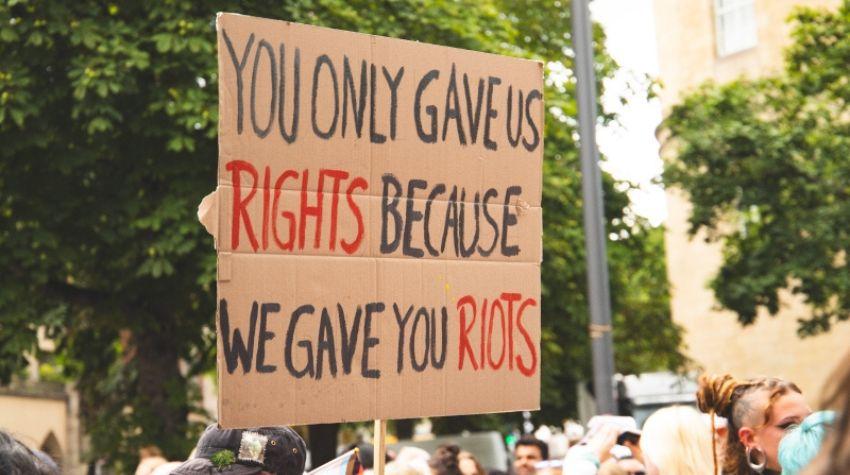 Ein Protestschild mit der Aufschrift "You only gave us rights because we gave you riots"
