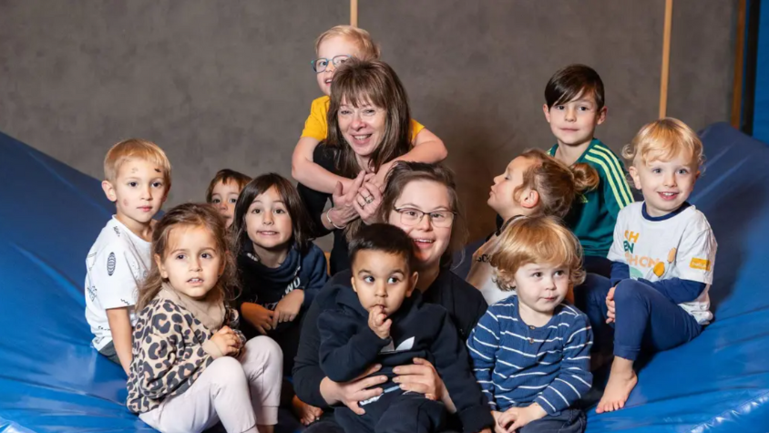 Annette umgeben von gesunden und beeinträchtigten Kindern auf einer Sportmatte