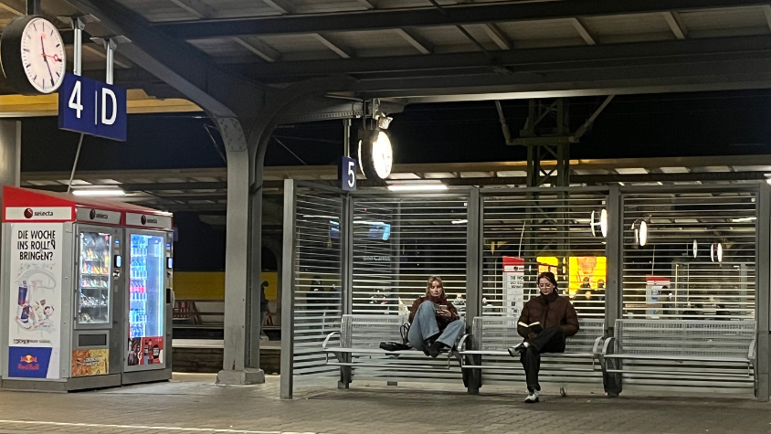 Zwei Leute warten am Bahnhof.