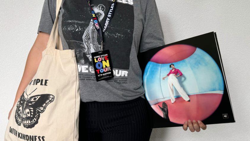 Person mit mehreren Harry Styles Merch-Artikeln