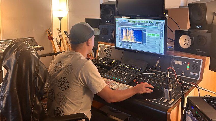 Musikproduzent Kilian Mohns sitzt vor seinem Mischpult und Computer und arbeitet an einem Song.