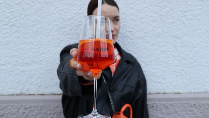 Frau die Aperolglas in die Kamera hält.