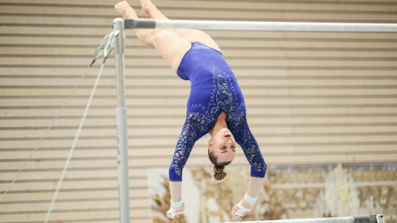 Carina Kröll ist im Handstand über Kopf am Stufenbarren zu sehen.